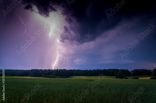 Gewitter/Blitz über Feld und Waldlandschaft