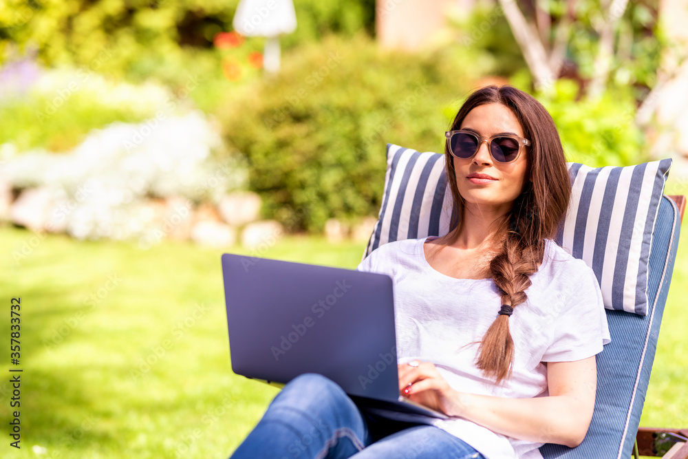 Young woman working on laptop in the garden Young woman working on laptop in the garden