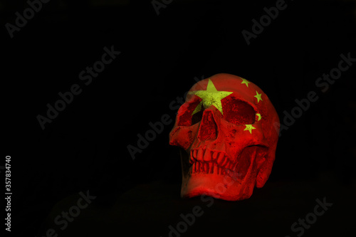 A white skull isloated aginst a plain black background with the Chinese National Flag projected over it. photo