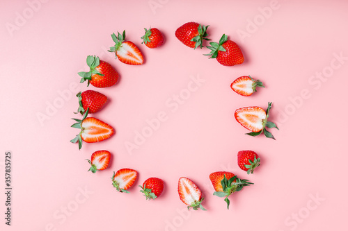 round frame made of fresh tasty strawberries on a pink background. Beautiful background or greeting card. copy space, flat lay, border.