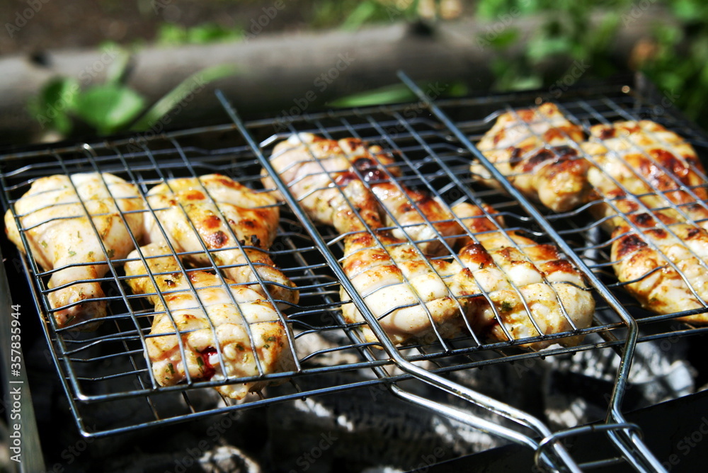 chicken legs are grilled on the grill in nature