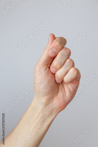 Gesture and sign, male hand holds something on a light background