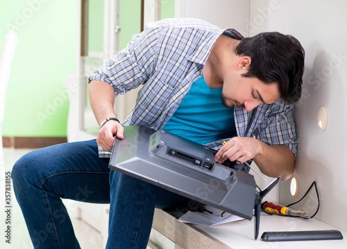 Young man husband repairing tv at home