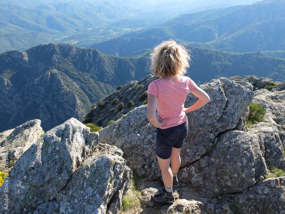 Naklejka premium jeune femme blonde devant le vide de la montagne du Caroux au soleil couchant du parc naturel du haut languedoc