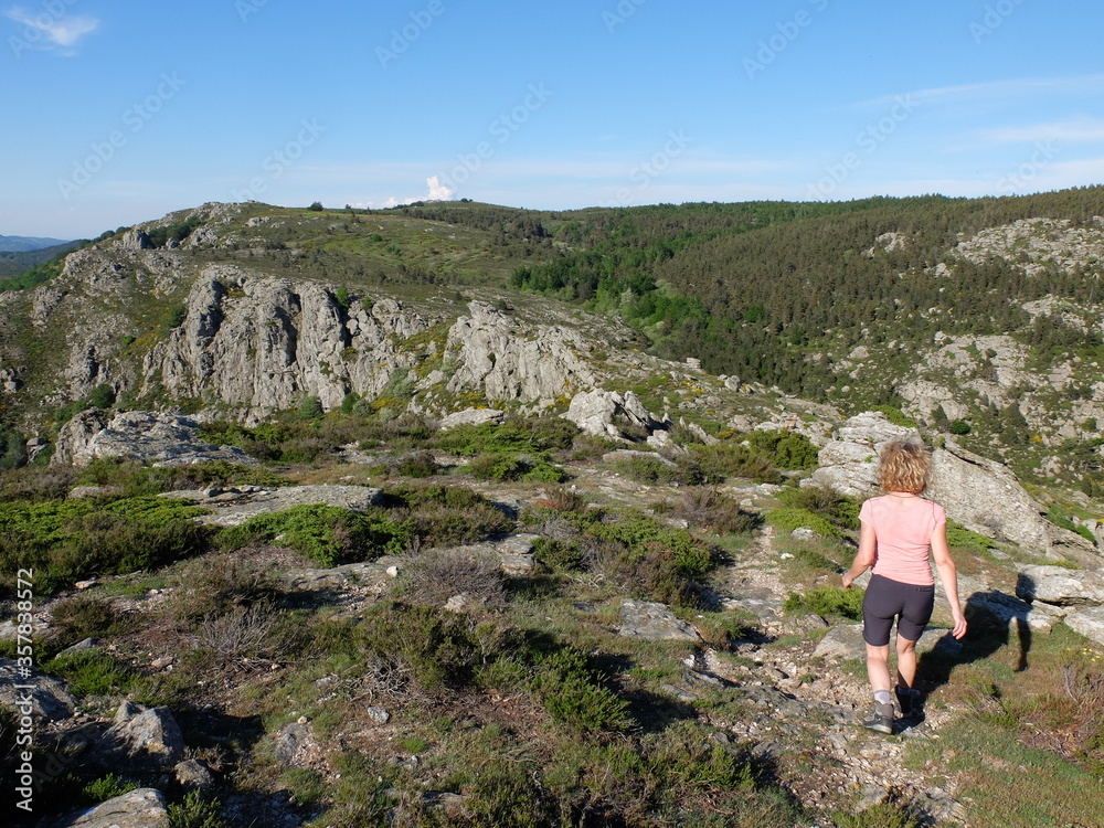 Jeune femme marchant en randonnée sur le plateau de montagne du Caroux du parc naturel régional du Haut Languedoc Jeune femme marchant en randonnée sur le plateau de montagne du Caroux du parc naturel régional du Haut Languedoc