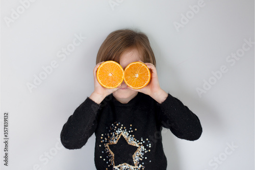 Niña con naranjas en los ojos y con un jersey negro con una estrella de purpurina