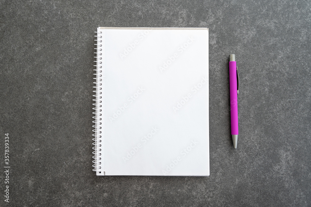 Top down view of pink pen placed next to an empty notebook which has place for copy space Top down view of pink pen placed next to an empty notebook which has place for copy space