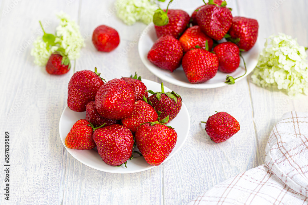 Large ripe strawberries are collected from the garden. On a white wooden background. Homemade winter fruit blanks. Selective focus. Large ripe strawberries are collected from the garden. On a white wooden background. Homemade winter fruit blanks. Selective focus.