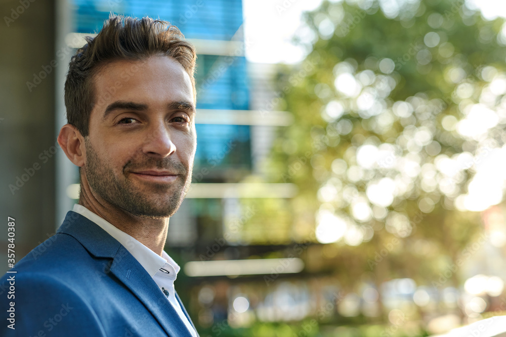Confident businessman smiling while standing outside in the city Confident businessman smiling while standing outside in the city