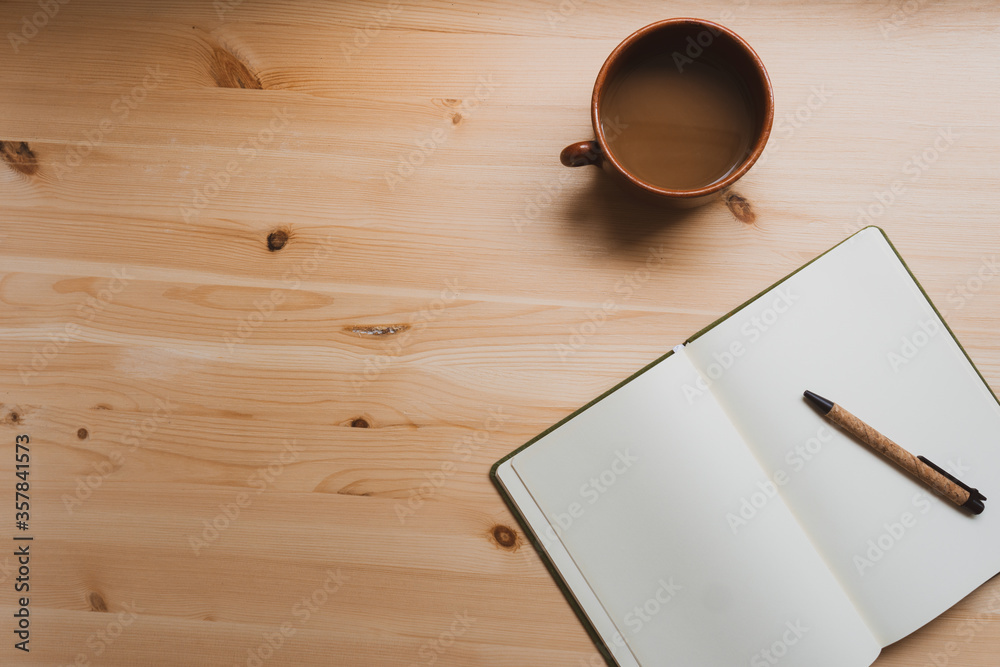Notebook, pencil and a cup of melted chocolate in the workspace. Natural pine table. Notebook, pencil and a cup of melted chocolate in the workspace. Natural pine table.
