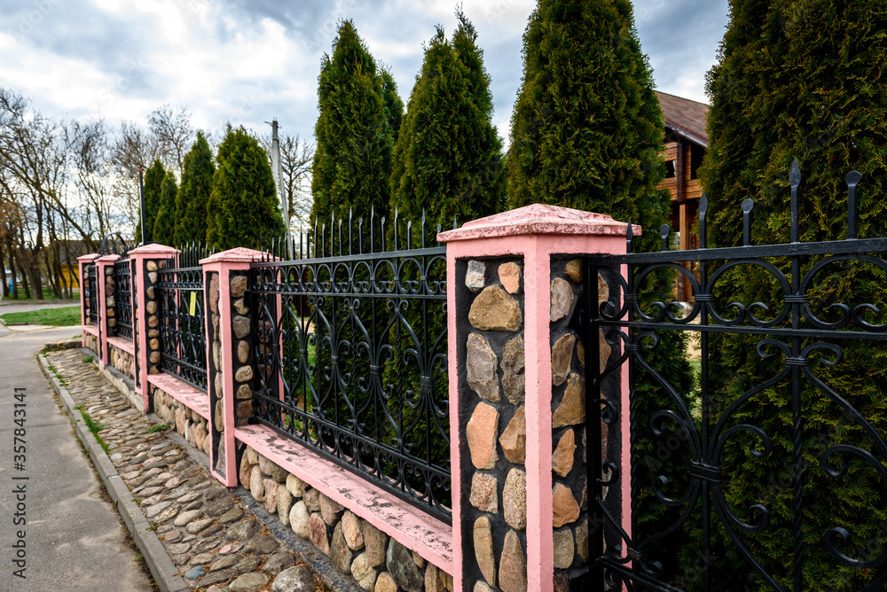 Wrought iron fence with stone posts. Fence of the private house. Wrought iron fence with stone posts. Fence of the private house.