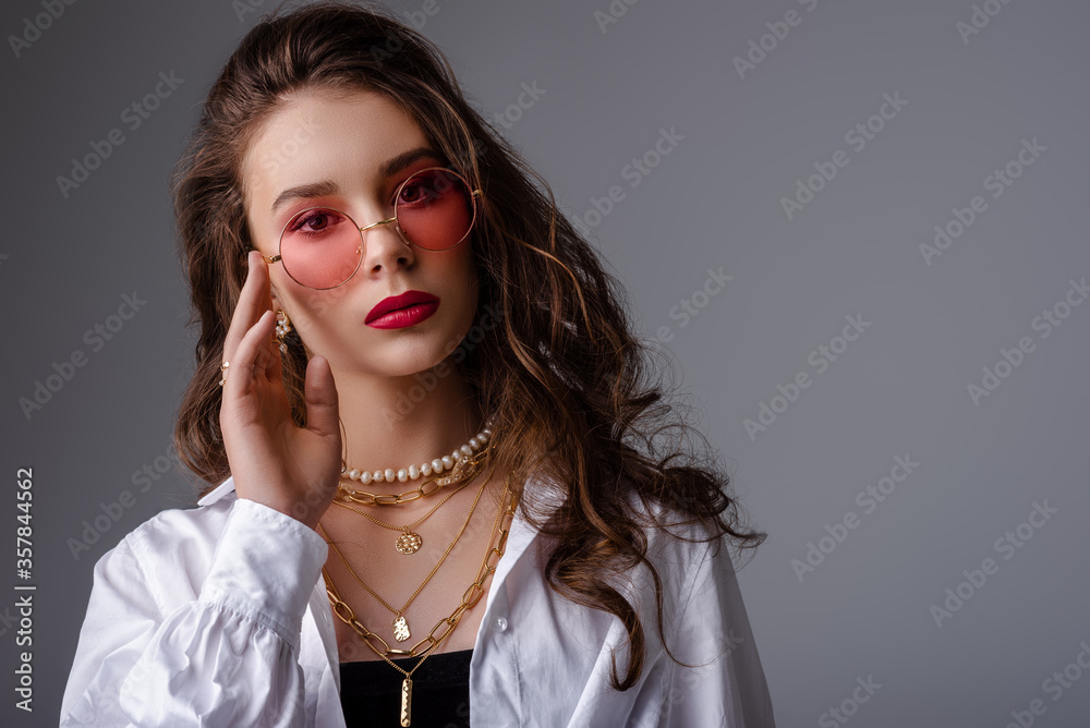 Fashionable model, woman wearing pink color sunglasses, trendy pearl necklace, many golden chains, classic white shirt. Clos up studio portrait. Copy, empty space for text