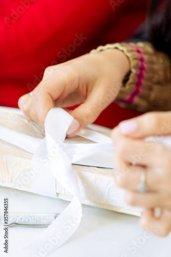 woman ties a ribbon on a gift