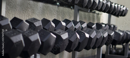 Many dumbbells on a specialized rack for dumbbells. Sport, fitness, weightlifting, healthy lifestyle. Exercise in the fitness room.
