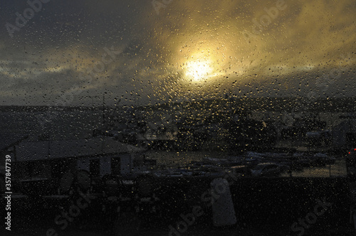 Vue à travers la vitre d'un pub, couverte de gouttes de pluie dûe à l'orage, sur le petit port de Baltimore à la pointe sud de l'Irlande.
