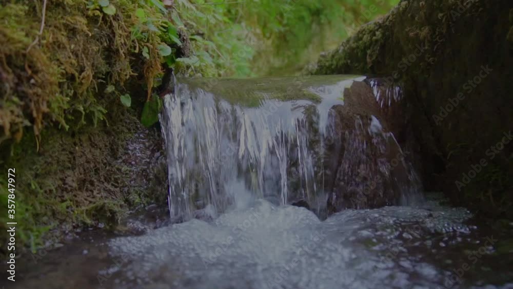 Slow forward shot showing little waterfall in forest during summer season Slow forward shot showing little waterfall in forest during summer season