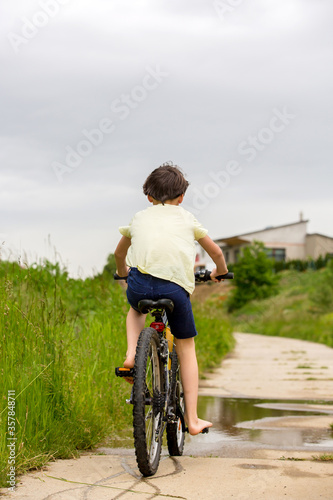 Child, boy, riding bike in muddy puddle, summer time