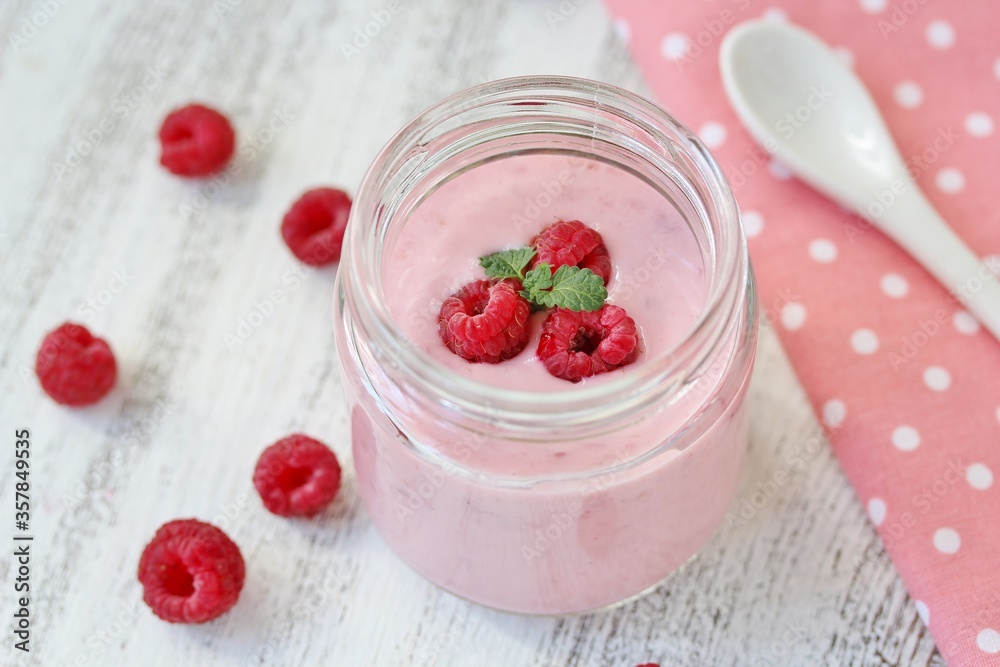 Homemade raspberries yoghurt  and raspberry berries in a jar. light background. Soft focus. pink. copy space