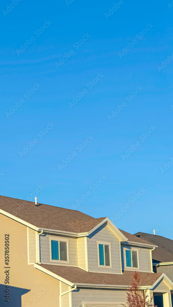 Vertical Homes with horizontal wall sidings and front gable roofs againts clear blue sky Vertical Homes with horizontal wall sidings and front gable roofs againts clear blue sky