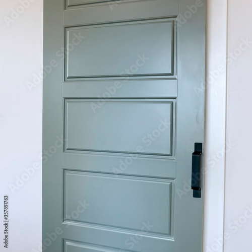 Square crop Closed sliding gray panel door with black handle against white wall of home
