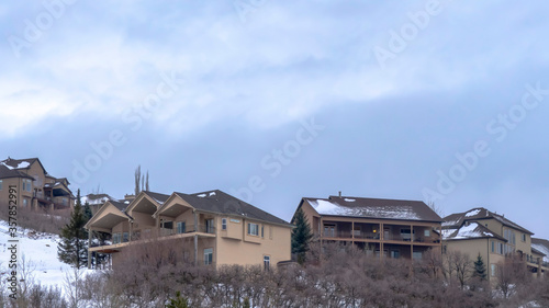 Panorama frame Cloudy blue sky over homes atop a hill covered with fresh white snow in winter