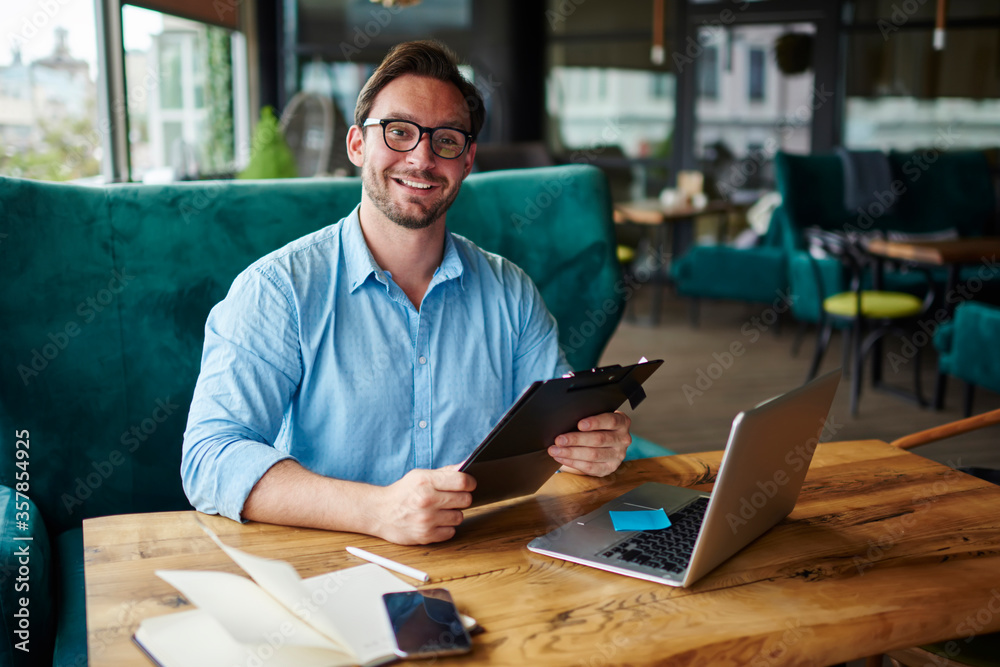 Portrait of successful businessman in trendy eyeglasses satisfied with creative job on startup.