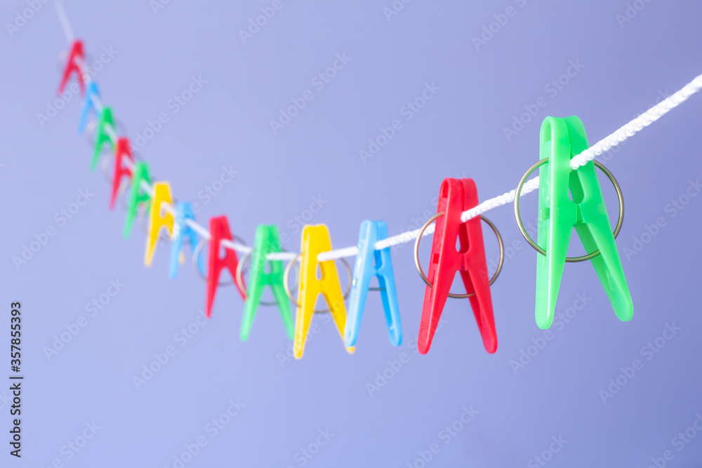 the selected focus is colored clothespins on a clothesline on a blurry background of blue grainy paper