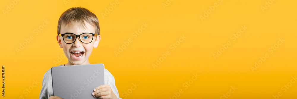 Happy child boy  holding a tablet ipade for your information on the blue background - obrazy, fototapety, plakaty 