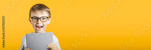 Happy child boy  holding a tablet ipade for your information on the blue background