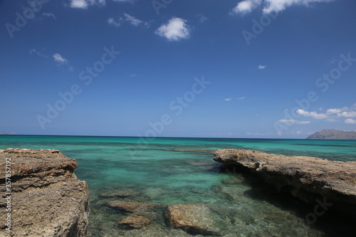 panorama landscape scenic view of isolated deserted rocky beach with blue turquoise sea water and sky with white clouds background on beautiful and colorful Mallorca island in Spain © Liza