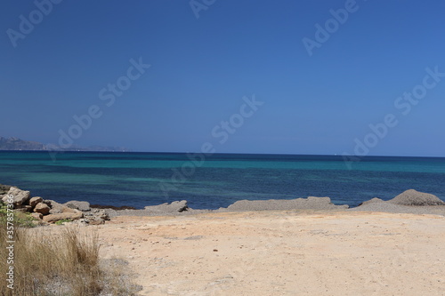 panorama landscape scenic view of isolated deserted rocky white yellow sand beach with blue turquoise sea water and sky background on beautiful and colorful Mallorca island in Spain © Liza