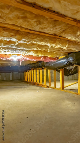 Vertical crop Basement or crawl space with upper floor insulation and wooden support beams © Jason