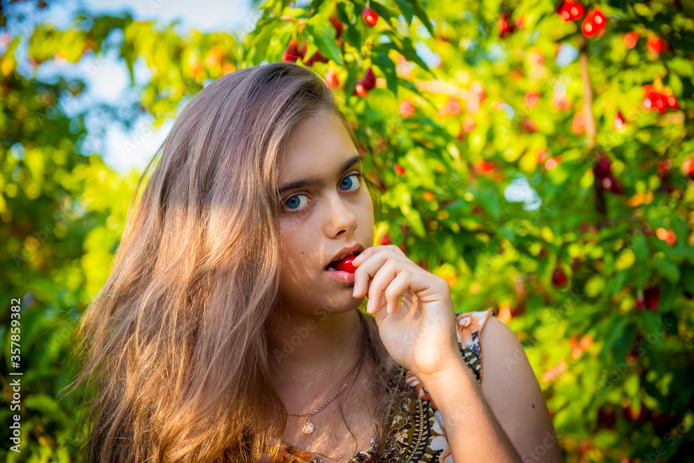 Sweet Girl Eats Cherry in the Garden. Young girl and sweet cherry. Portret beautiful girl in the cherry orchard. Sweet cherry. Fruit picking season. Summer fruits. Natural Vitamins Sweet Girl Eats Cherry in the Garden. Young girl and sweet cherry. Portret beautiful girl in the cherry orchard. Sweet cherry. Fruit picking season. Summer fruits. Natural Vitamins