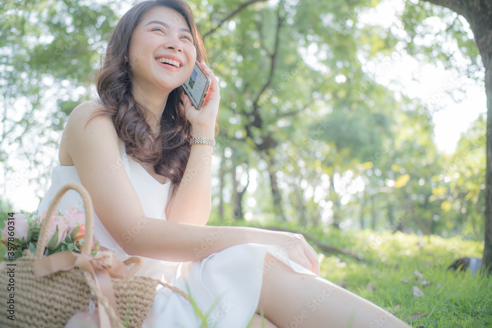 Beautiful asian women talking smart phone in city park Beautiful asian women talking smart phone in city park