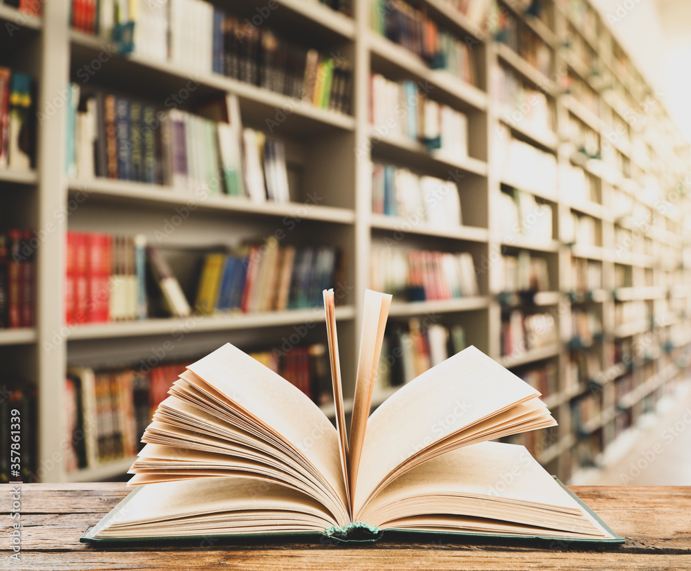 Open hardcover book on wooden table in library Open hardcover book on wooden table in library