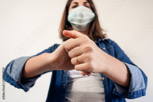 Woman with medical protection mask cleaning her hands.