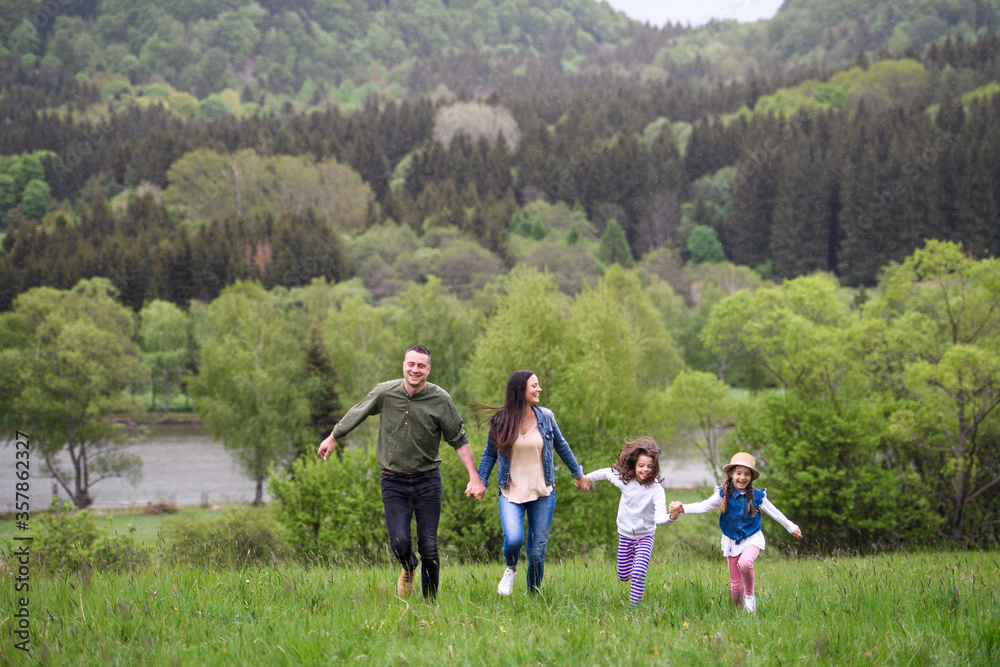 Happy family with two small daughters running outdoors in spring nature. Happy family with two small daughters running outdoors in spring nature.