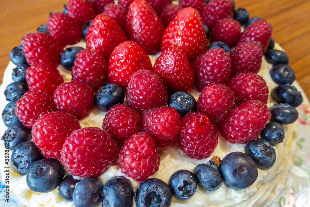 A cake decorated with butter icing and summer fruits including strawberries, raspberries and blueberries. A cake decorated with butter icing and summer fruits including strawberries, raspberries and blueberries.