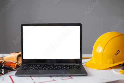 laptop and construction items, yellow helmet, apartment plan on the table, text, construction concept nobody