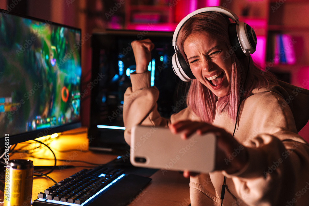 Image of girl taking selfie on cellphone while playing video game Image of girl taking selfie on cellphone while playing video game