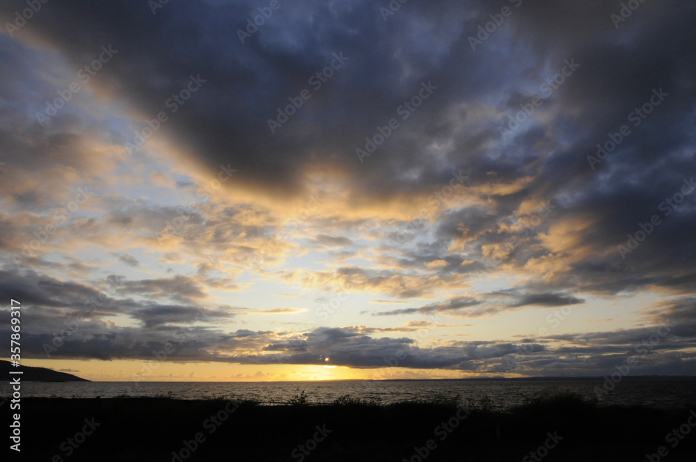 Beau coucher de soleil au dessus de la mer à l'ouest de l'Irlande. Vagues, nuages et ciel bleu, doré, jaune orangé.