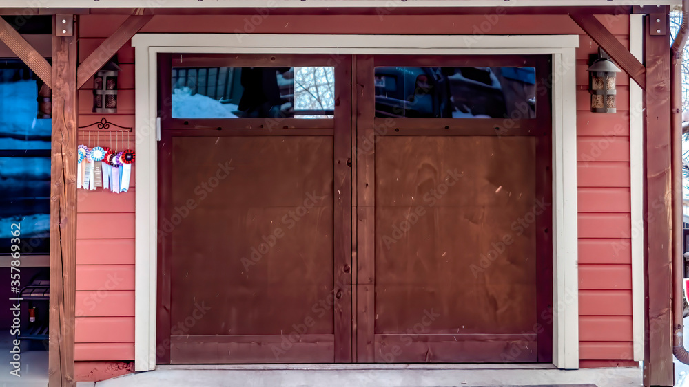 Panorama frame Brown wooden glass panelled garage door of home under snowy roofs in winter Panorama frame Brown wooden glass panelled garage door of home under snowy roofs in winter
