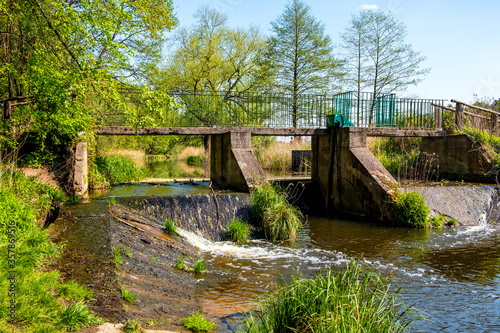 Vintage footbridge with retention rapids and weirs over Czarna River nature reserve near Piaseczno town in Mazovia region of Poland