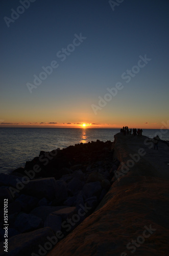 太平洋の初日の出を岩場で眺める人々 © palzafenon