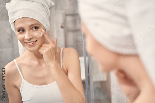 Smiling attractive Caucasian woman applying a moisturizer