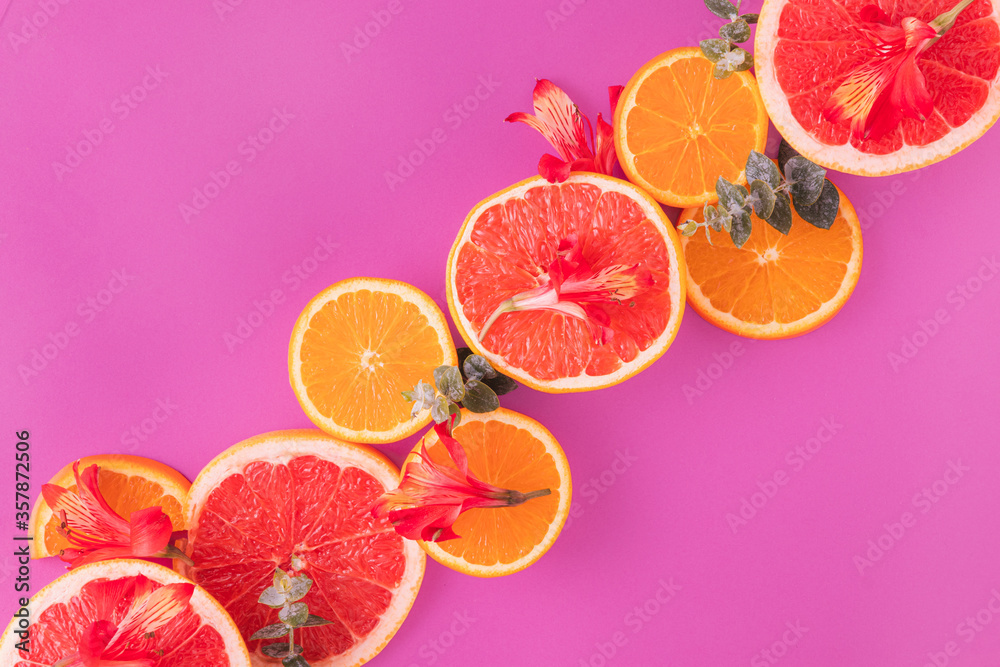Fruit frame made of slices of citrus fruits (orange, grapefruit) with red flowers in a purple background Fruit frame made of slices of citrus fruits (orange, grapefruit) with red flowers in a purple background