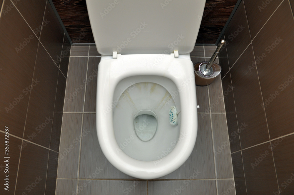 Fototapeta premium A white toilet with traces of rust from the flushing water. Hygiene