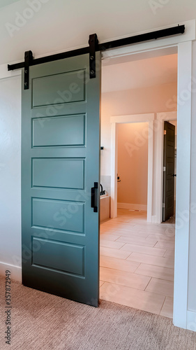 Vertical Sliding gray wooden panel door that leads to the bathroom of a home