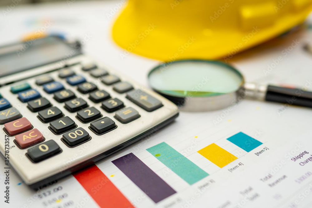 Calculator with .yellow construction helmet on chart and graph paper. Finance development, Banking Account, Statistics, Investment Analytic research data economy, Stock exchange trading. Calculator with .yellow construction helmet on chart and graph paper. Finance development, Banking Account, Statistics, Investment Analytic research data economy, Stock exchange trading.