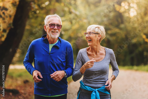 Fototapeta Naklejka Na Ścianę i Meble -  Smiling senior couple jogging in the park